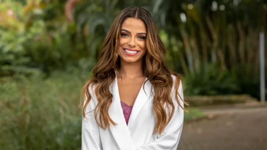 Key Alves de blazer branco, cabelo solto, sorrindo durante gravação para a TV Globo