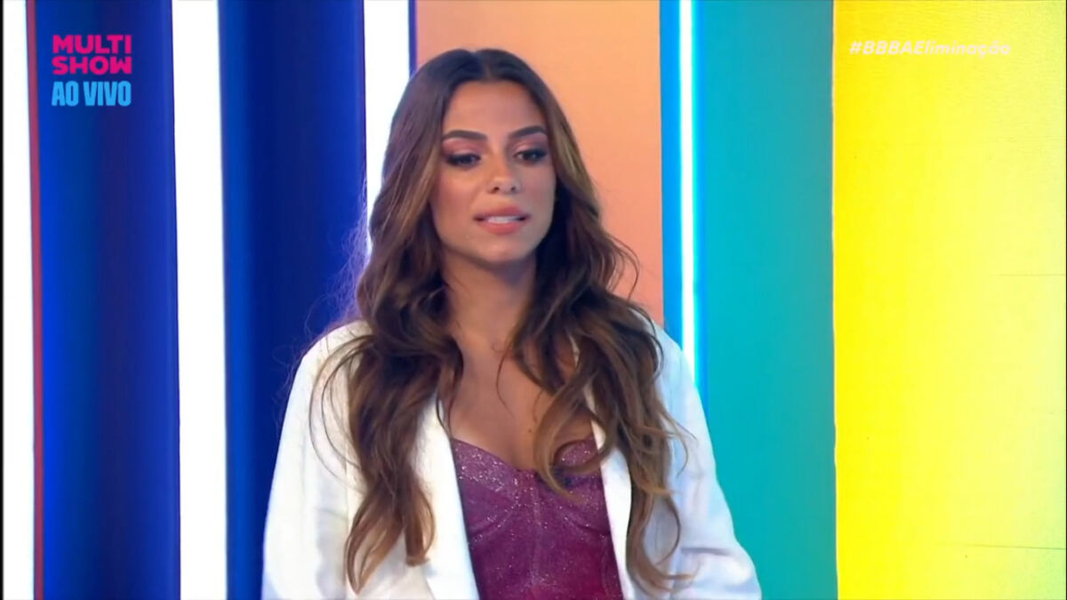 Key Alves de blazer branco, camiisa roxa, em pé durante gravação de programa de TV