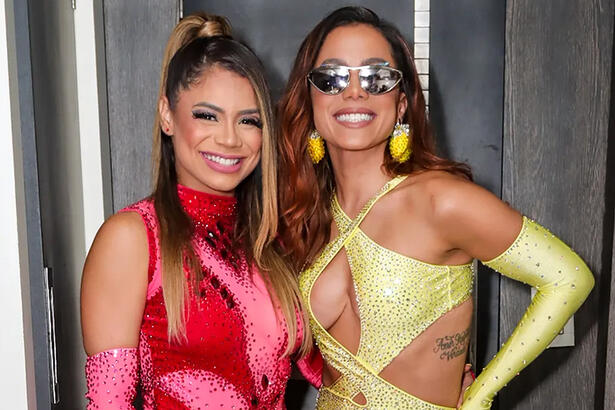 Lexa de look vermelho e Anitta de look amarelo, sorrindo, durante bastidor de show em Natal