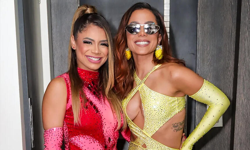 Lexa de look vermelho e Anitta de look amarelo, sorrindo, durante bastidor de show em Natal