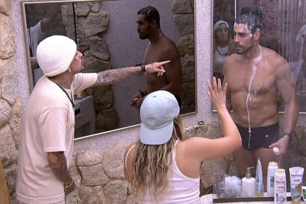 MC Guimê apontando para Cara de Sapato, que está tomando banho, durante discussão no banheiro do BBB 23. Bruna Griphao entre eles, tendo interferir e apaziguar
