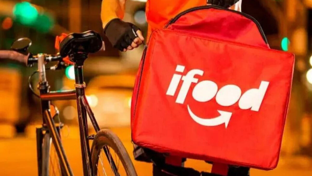 Um entregador de bicicleta ajeitando a mochila de entrada do iFood