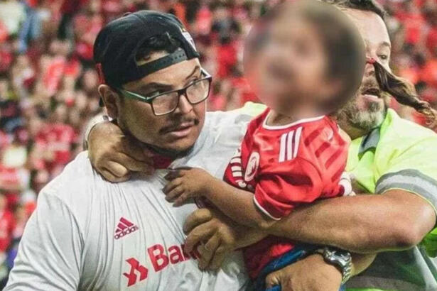 Torcedor do Internacional, com uma criança no colo, sendo retirado por seguranças após invadir o gramado