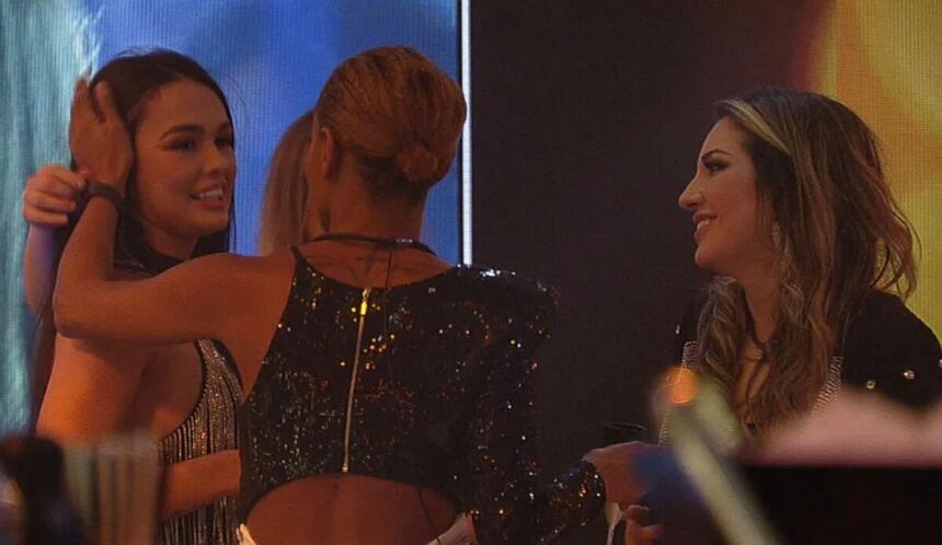 Larissa recebendo abraços de Aline que está de costa na imagem, Amanda, que está de frente e Bruna.