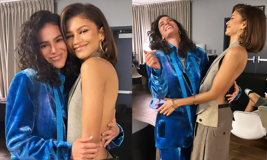 Bruna Marquezine de blazer e calça azul, sorrindo, abraçando Zendaya nos bastidores de evento