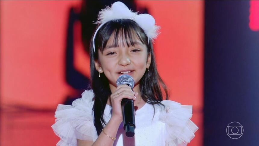Dani Harumi se apresenta, sorrindo, no palco do The Voice Kids Brasil 8