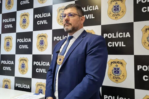 Delegado Charles Leão posando em frente a um banner da Polícia Civil