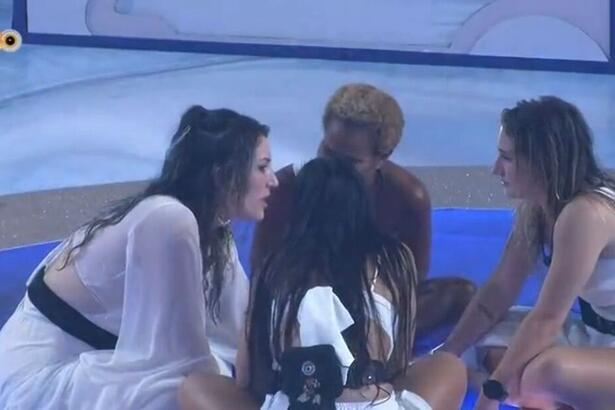 Aline sentada no chão da festa do BBB 23. Do seu lado direito está Amanda e do seu esquerdo Bruna. Larissa se encontra de costas para a imagem.