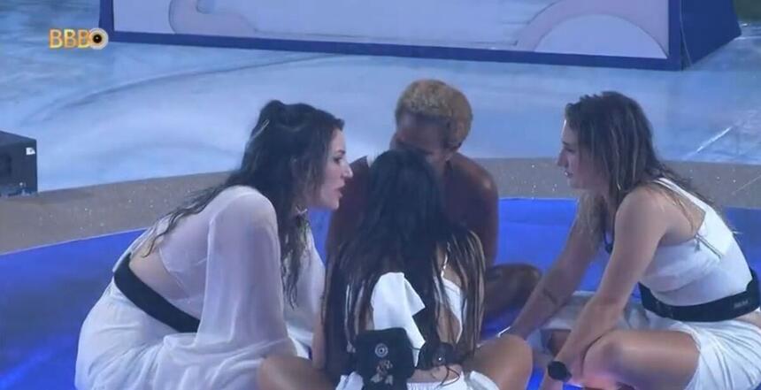 Aline sentada no chão da festa do BBB 23. Do seu lado direito está Amanda e do seu esquerdo Bruna. Larissa se encontra de costas para a imagem.