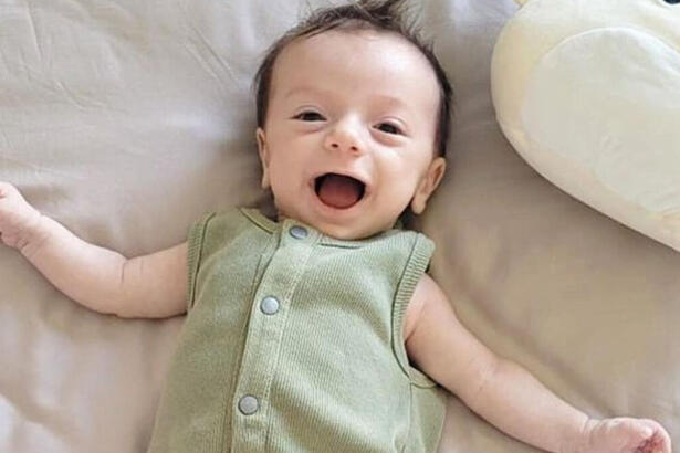 Luca, filho de Claudia Raia, sorrindo em uma foto deitada na cama