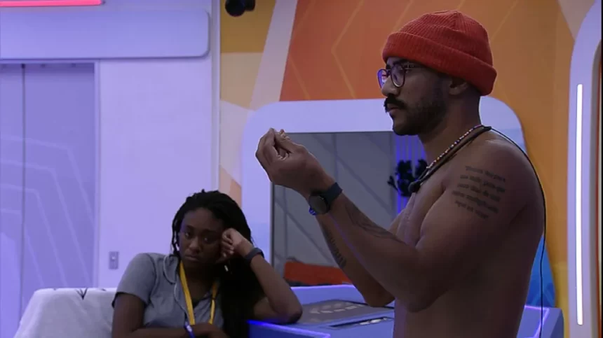 Ricardo sem camisa, com boina vermelha, em pé, no Quarto do Lider do BBB 23