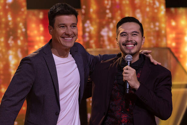 Rodrigo Faro ao lado e abraçado com um participante no palco do episódio de estreia do Canta Comigo 5