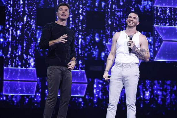 Rodrigo Faro sorridente conversando com San Oliver no palco do Canta Comigo 5