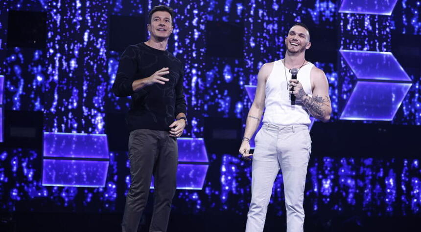 Rodrigo Faro sorridente conversando com San Oliver no palco do Canta Comigo 5