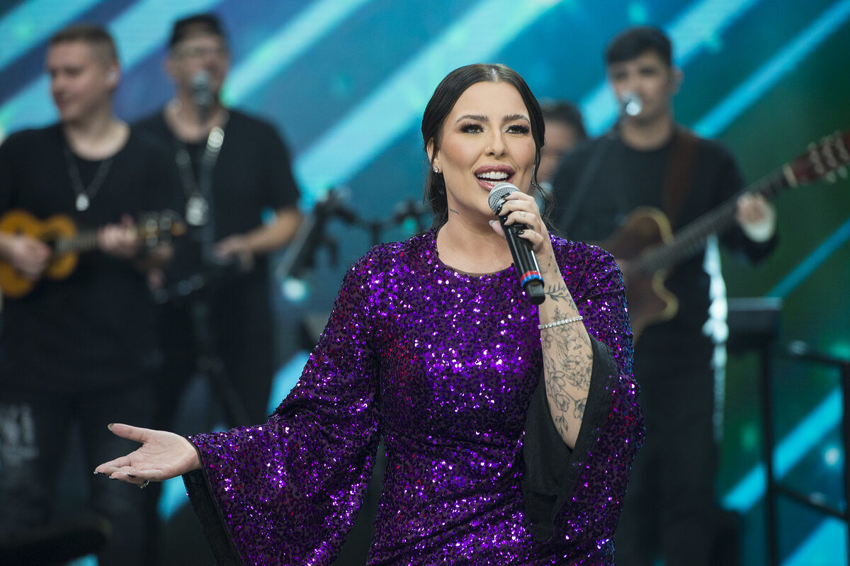 Ana Clara abre os braços enquanto canta no palco do Faustão na Band