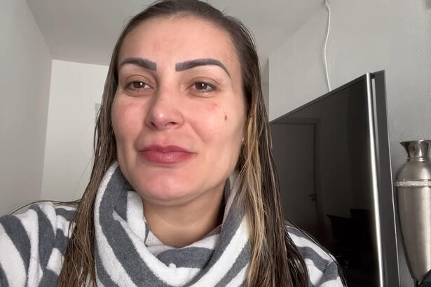 Andressa Urach em trecho do seu vlog, na sala da sua casa, com uma televisão ao fundo