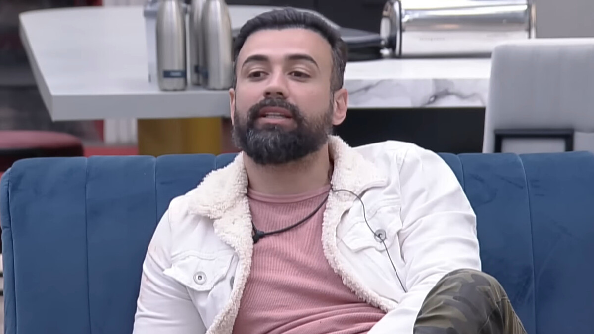 Bruno Tálamo sentando no sofá da sala do A Grande Conquista