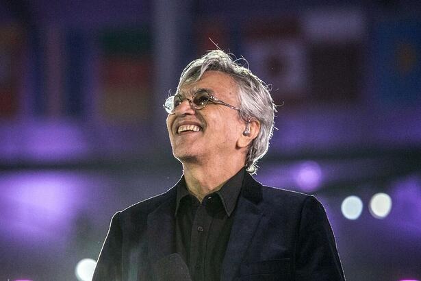 Caetano Veloso sorrindo, olhando pra cima durante apresentação em São Paulo