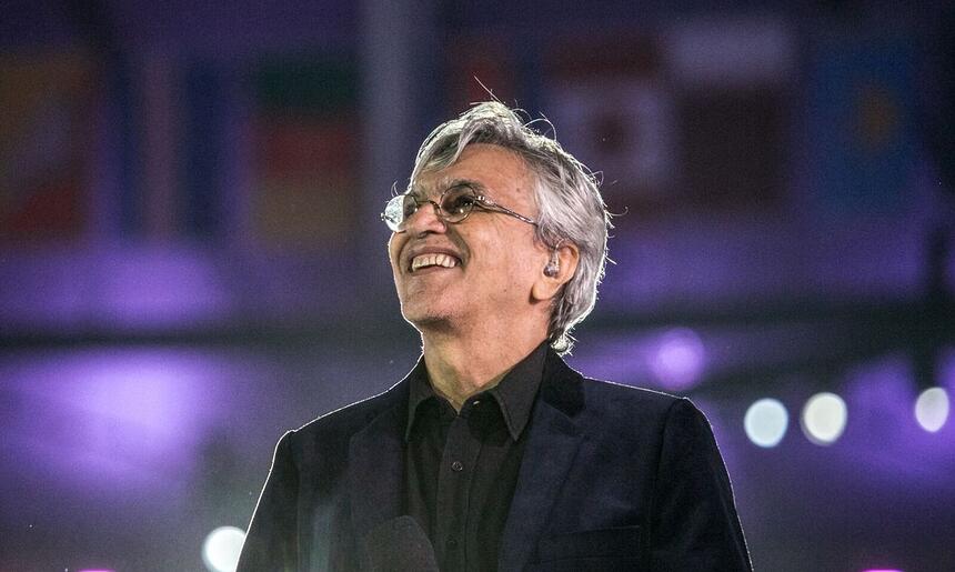 Caetano Veloso sorrindo, olhando pra cima durante apresentação em São Paulo