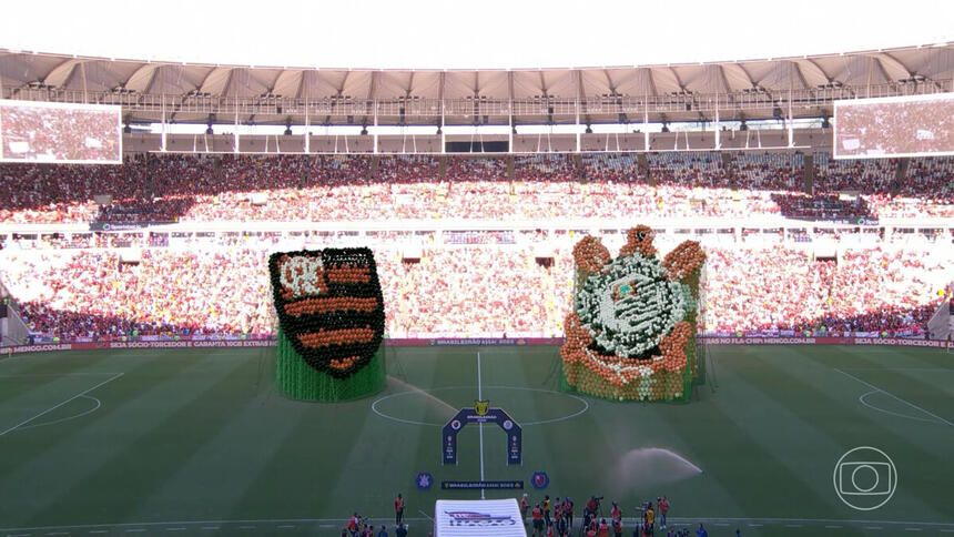 Trecho da transmissão da TV Globo no jogo entre Flamengo e Corinthians, com os logos da equipe no gramado do Maracanã