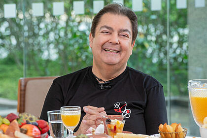 Faustão sentado na mesa de café da manhã, em uma participação antiga no Mais Você