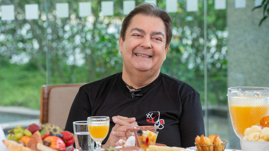 Faustão sentado na mesa de café da manhã, em uma participação antiga no Mais Você