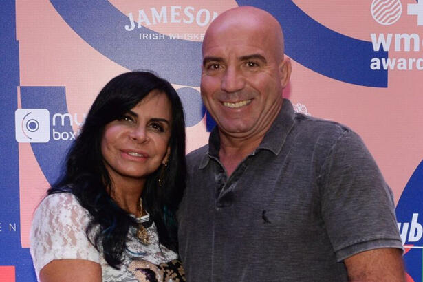 Gretchen e Carlos Marques posando juntos e abraçados nos bastidores de um evento