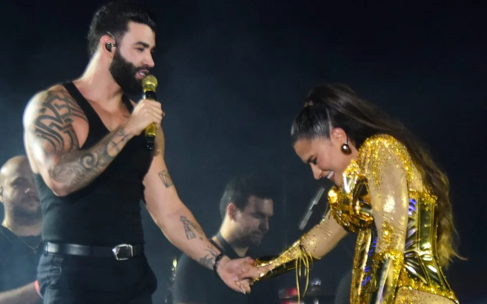 Gusttavo Lima pegando na mão de Simone durante show em festival