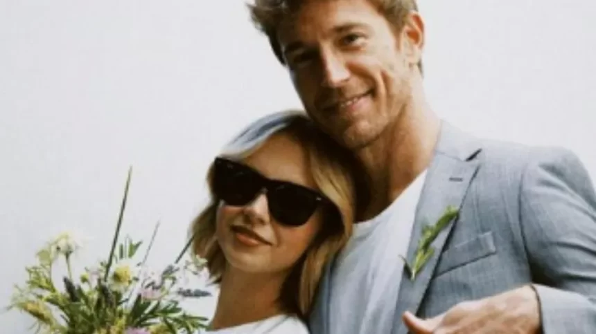 Isabella Scherer de vestido branco e oculos de sol preto; Rodrigo Calazans atrás de Isabella, sorrindo, de blazer cinza e camisa básica branca