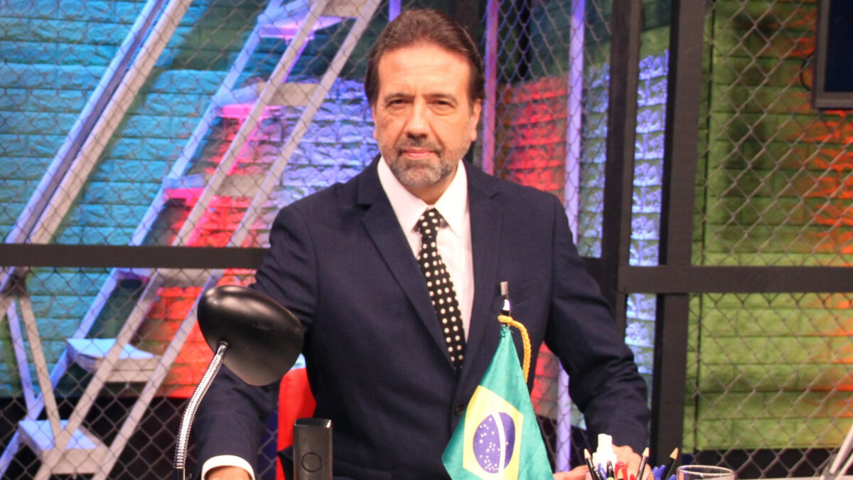 Jorge Lordello em foto posada, sentado em uma mesa, no estúdio do Hora de Ação