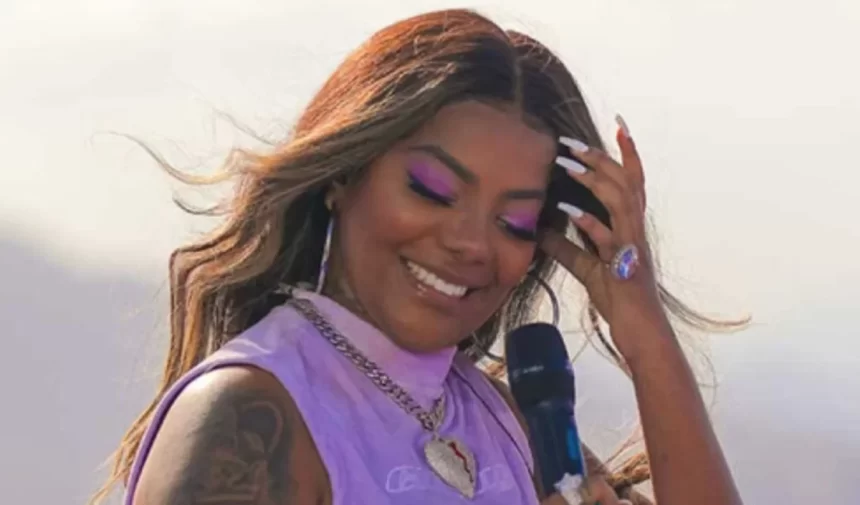 Ludmilla de cabelo solto, sorrindo, com a mão no cabelo