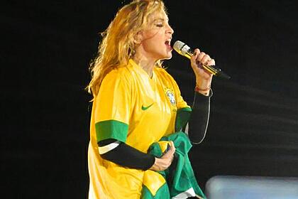 Madonna com a camisa da seleção brasileira, segurando o microfone