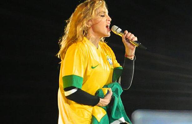 Madonna com a camisa da seleção brasileira, segurando o microfone