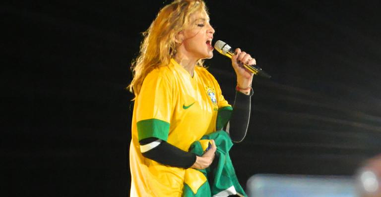 Madonna com a camisa da seleção brasileira, segurando o microfone