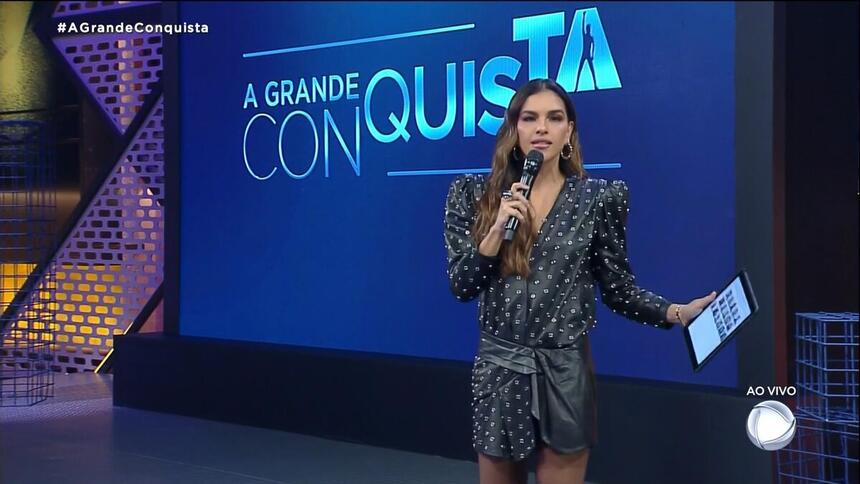 Mariana Rios em frente ao telão, em trecho da estreia do reality A Grande Conquista
