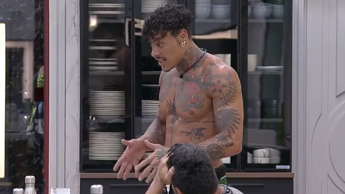 Murilo Dias, sem camisa, gesticulando com as mãos durante conversa na cozinha do A Grande Conquista