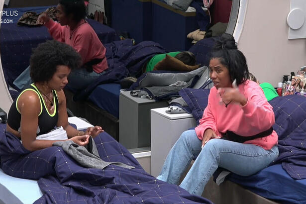 Natália e Janielle sentadas na cama durante conversa no quarto do A Grande Conquista