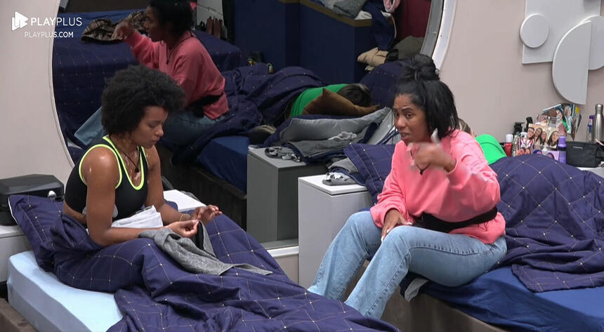 Natália e Janielle sentadas na cama durante conversa no quarto do A Grande Conquista