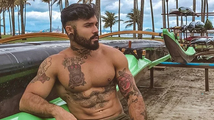 Paulo Vitor encostado no carro, sem camisa, de perfil