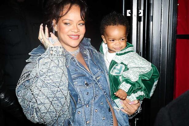 Rihanna sorrindo, segurando o filho no braço esquerdo