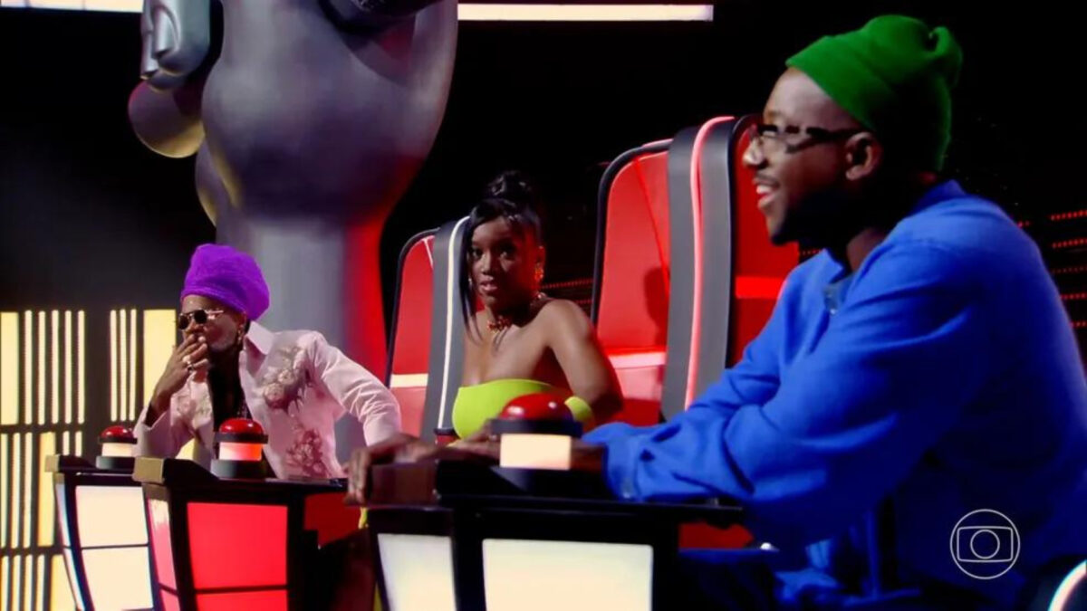 Carlinhos Brown, IZA e Mumuzinho sentados na cadeira de técnico do The Voicde Kids 8