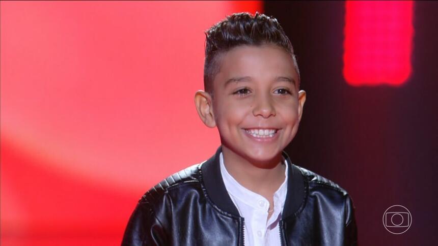 Marlysson Reis sorrindo no palco do The Voice Kids 8. Cantor mirim passa para a próxima etapa do programa