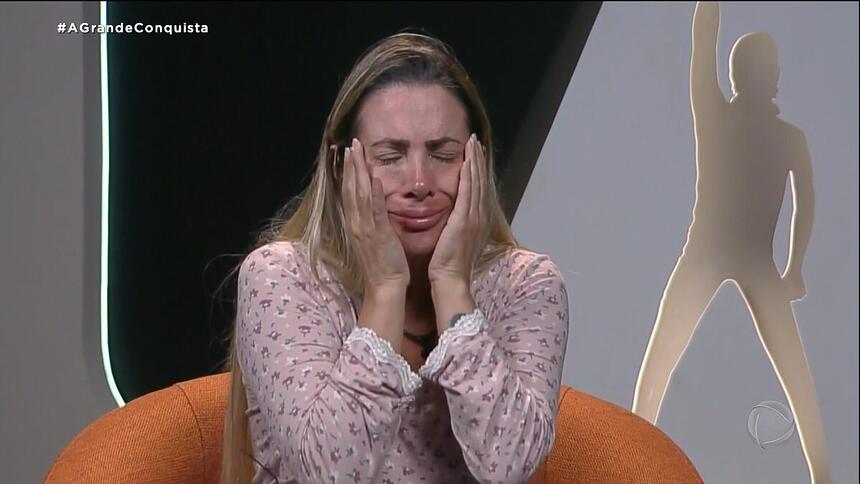 Faby Monarca coloca as mãos no rosto e chora dentro da cabine do A Grande Conquista antes de desistir do programa