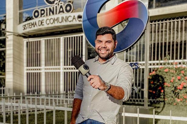 Repórter Alex Silvestre segura microfone da Record TV na frente da sede da TV Guararapes em Pernambuco