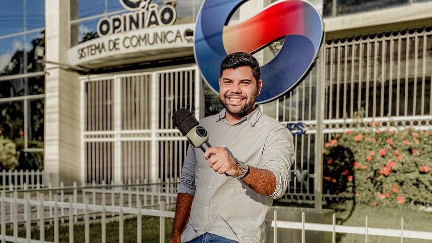 Repórter Alex Silvestre segura microfone da Record TV na frente da sede da TV Guararapes em Pernambuco