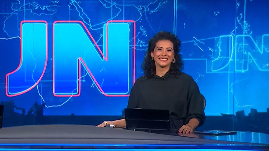 Aline Midlej sorrindo, na bancada do Jornal Nacional, ainda grávida de sua filha Celeste