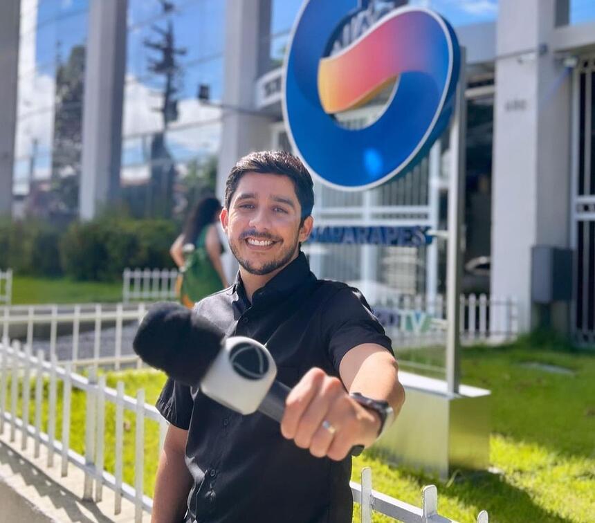 Anderson Souza segura o microfone da Record TV em frente a sede da TV Guararapes em Recife, Pernambuco