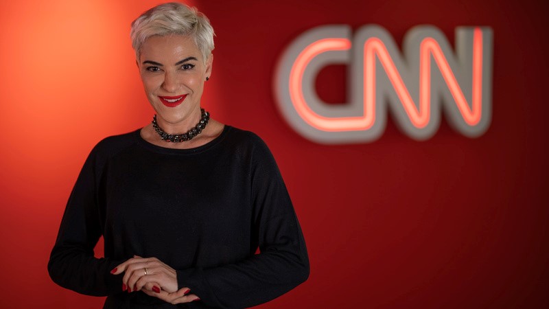 Fabíola Kassin no cenário da CNN Brasil com o logo do canal ao fundo