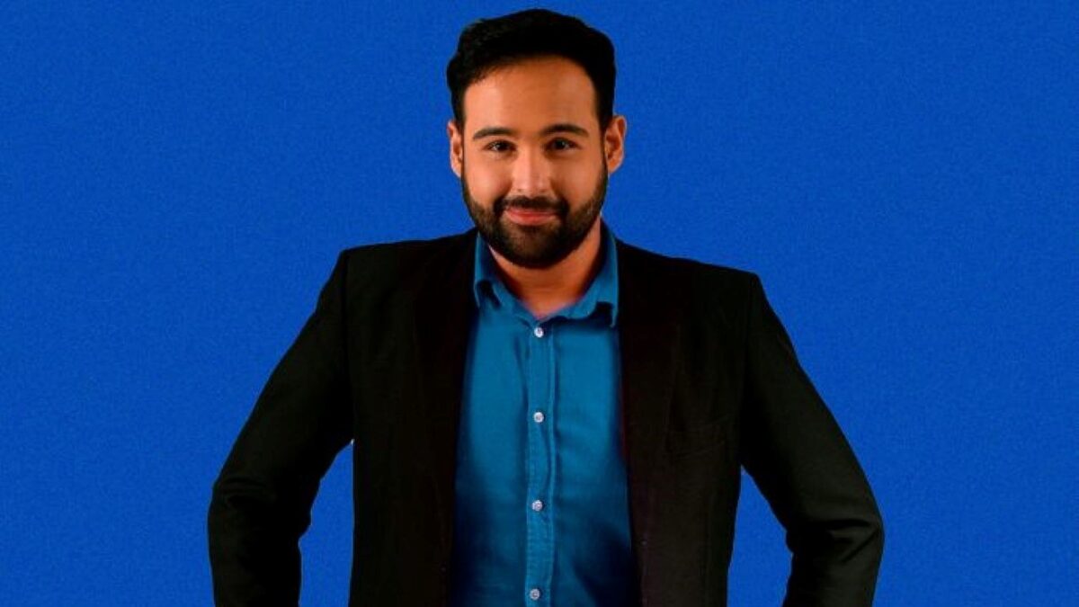 Pablo Marques de terno preto e camisa azul sorrindo em foto de lançamento do podcast do venenoso na TV Guararapes