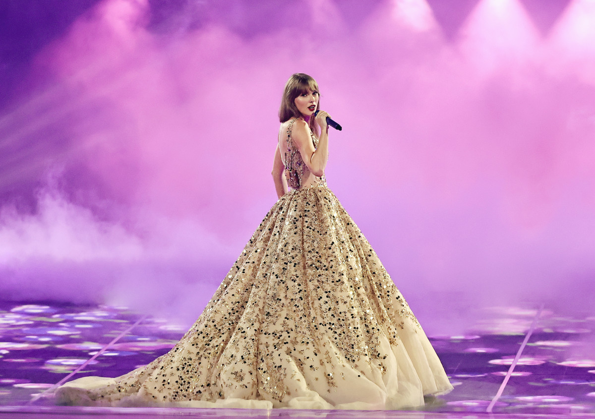 Taylor Swift com um longo vestido dourado na turnê The Eras Tour. Cantora anuncia shows no Brasil.